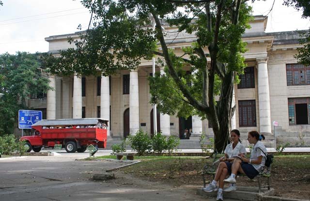 A passenger truck outside <em>Pre-Universitario Alvaro Morell,</em> and two of the students.