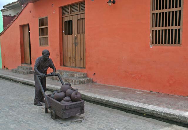 Statue of a man wheeling a barrow full of <em>tinajones.</em>
