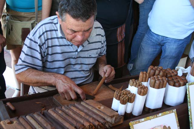 Cutting the surplus off a freshly rolled cigar at the tobacco <em>vega.</em>