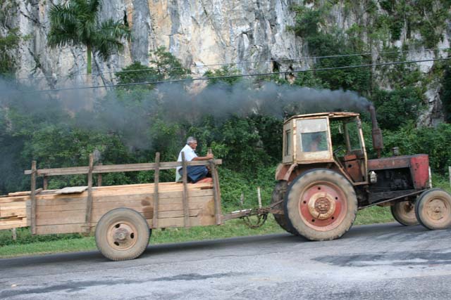 A tractor struggling up a hill in the Viñales valley, emitting the usual cloud of filth.