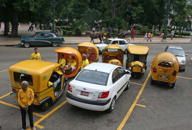 Coco-taxis and a modern taxi parked outside Hotel Inglaterra, central Havana.