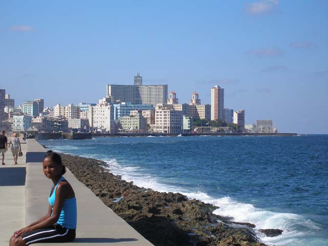 Sitting in the sun on Havana's <em>Malecón,</em> with the high-rises of Vedado behind.