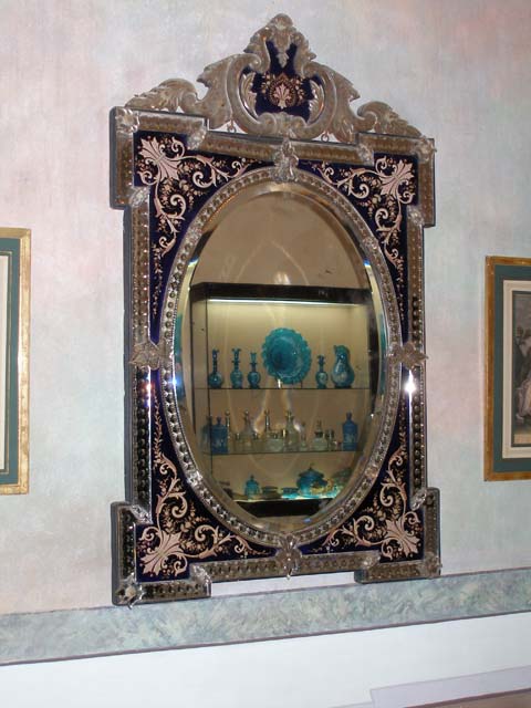 Elaborate mirror, showing blue glassware across the room.