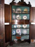 Corner cupboard with various porcelain on display.