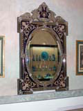 Elaborate mirror, showing blue glassware across the room.