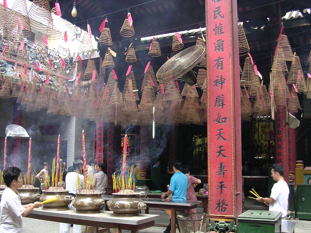 Sticks of incense burning as offerings in the pots. The spirals hanging up are also incense.