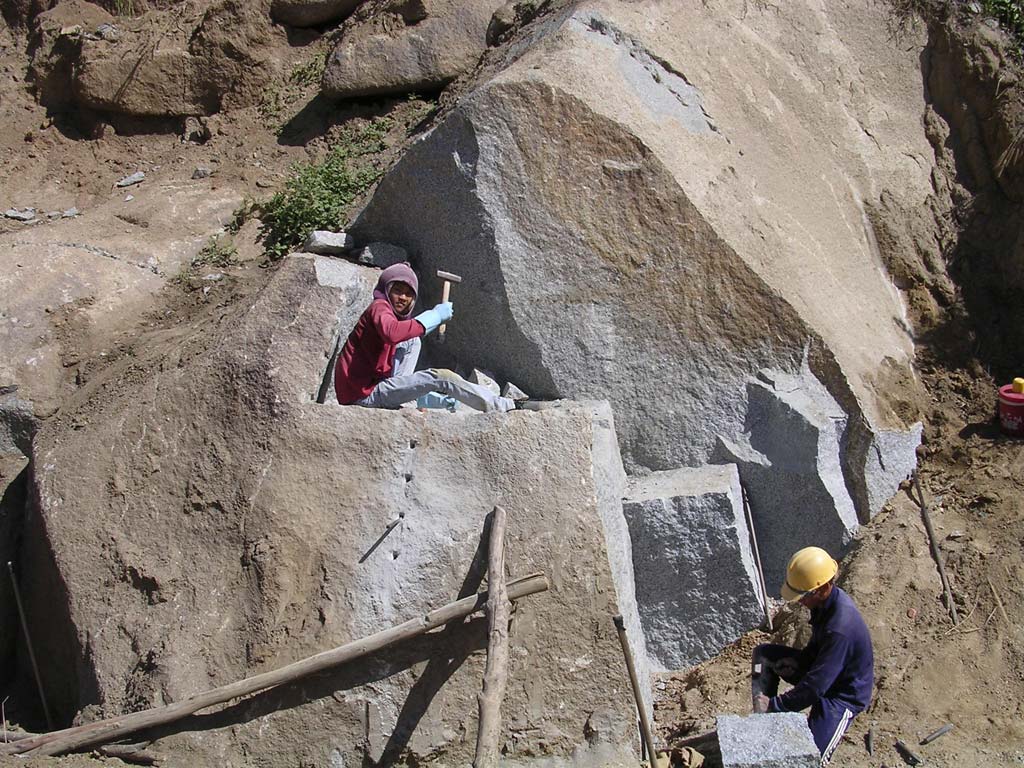 Breaking rocks to sell at a road cutting in the Central Highlands