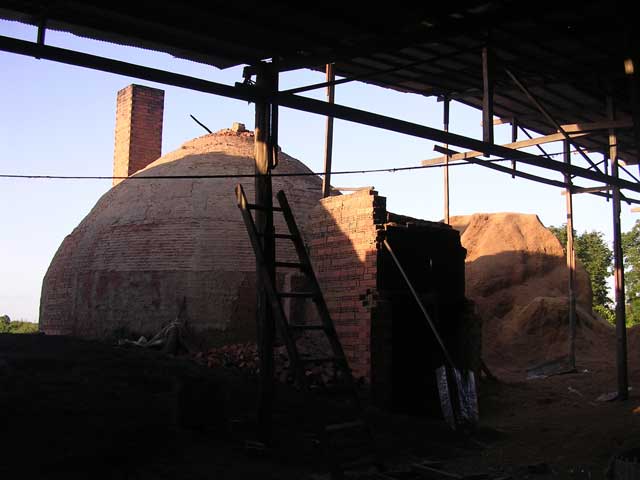 The kiln for firing the bricks - the big pile at the back is rice husks used for fuel