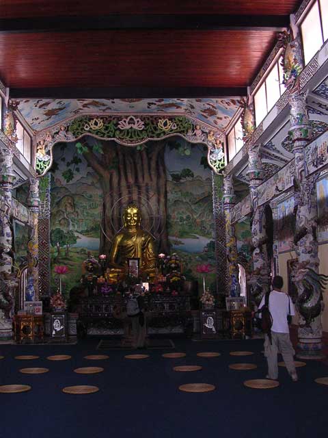 Buddha, complete with multiple neon halos, in front of the Bodhi Tree painting