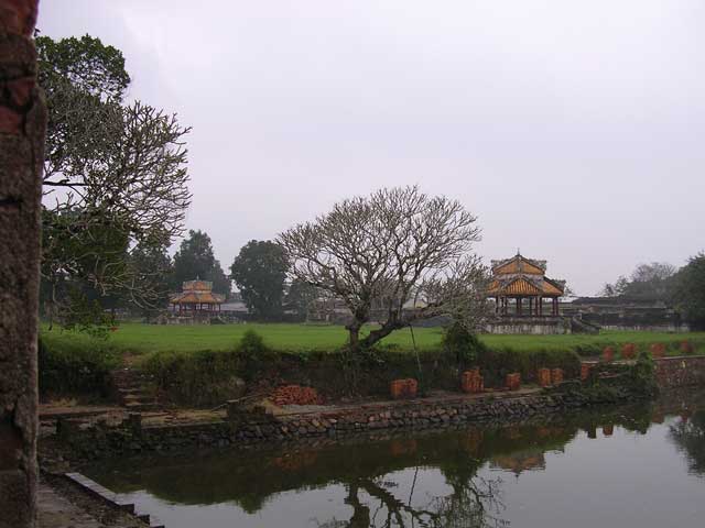 General view of water, grass, pavilions and rain