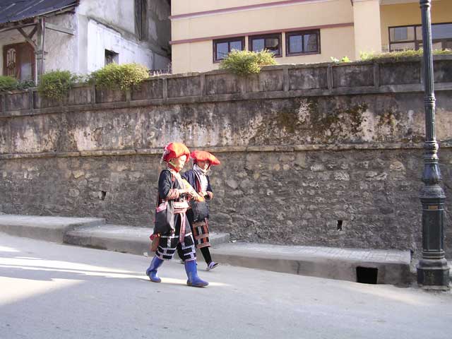 Two Dao women stride purposefully forth - one in blue wellies.