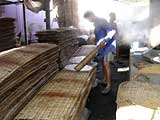 Laying the pancakes out on the drying racks at the rice paper factory