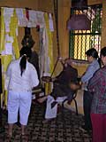 A monk delivering his teachings, with his hand on the beater for the big bell (mostly hidden behind the person in white)